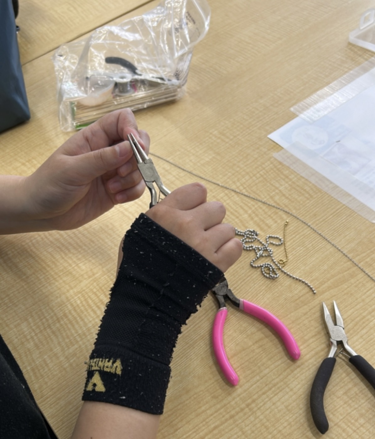 工具を使ってキーホルダーの金具を調整する手元